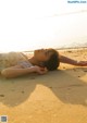 A woman laying on the sand at the beach.