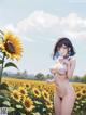 A woman in a bikini standing in a field of sunflowers.