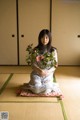 A woman sitting on the floor holding a bunch of flowers.