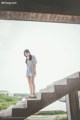 A woman standing on a set of stairs near a body of water.