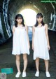 Two young women standing in a tunnel wearing white dresses.