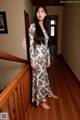 A woman standing on a wooden staircase in a long dress.