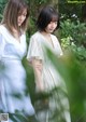 A couple of women standing next to each other in a forest.