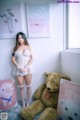 A woman standing next to a teddy bear in a room.